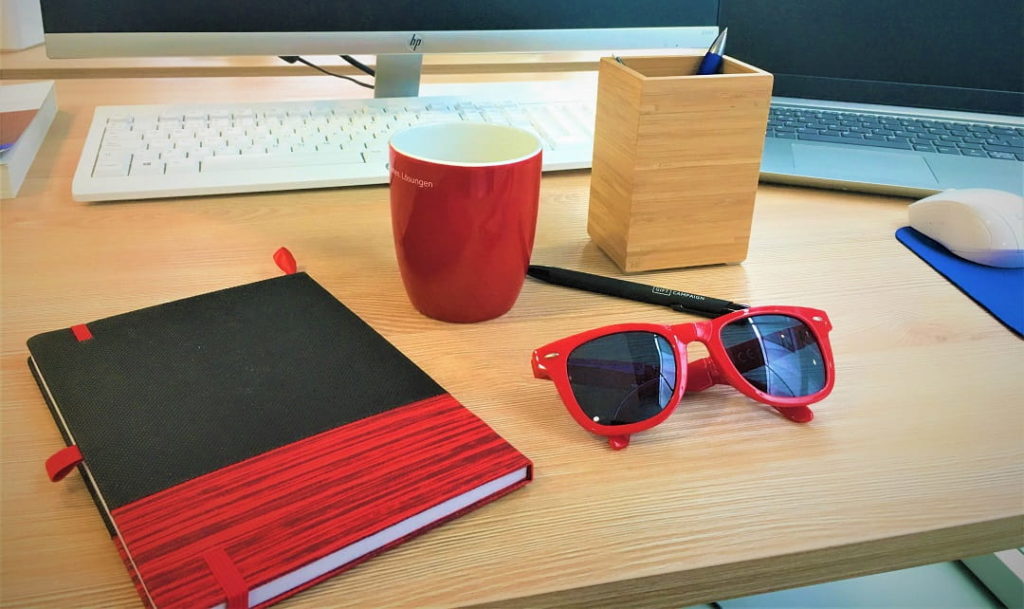 Notizbuch und Sonnenbrille als Werbegeschenke eines Begrüßungspaket für einen neuen Mitarbeiter.